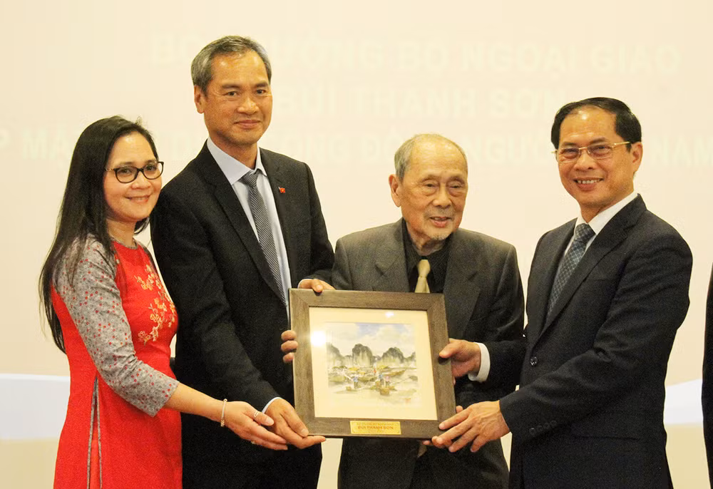 Bộ trưởng Bùi Thanh Sơn tặng quà lưu niệm cho đại diện Hội Người Việt Nam tại Pháp. (Ảnh: Khải Hoàn)