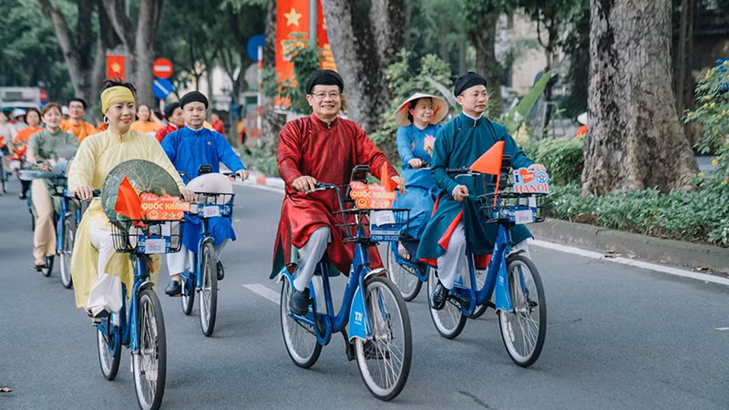 Người dân Thủ đô trong tà áo dài truyền thống đạp xe diễu hành trên đường phố Hà Nội tạo khung cảnh đẹp trong những ngày tháng Tám lịch sử. (Ảnh CHÍ DŨNG)