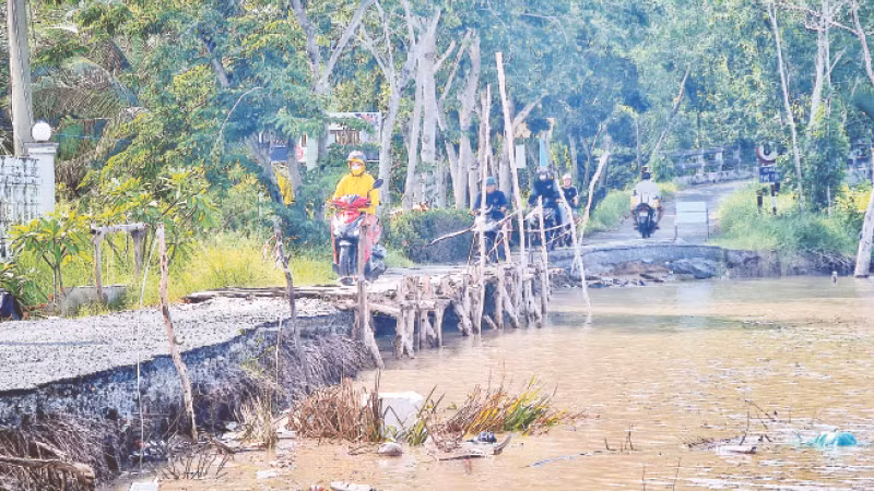 Tuyến đường về xã Tân Dân, huyện Đầm Dơi, người dân di chuyển bằng xe máy khó khăn do đường bị chia cắt vì sạt lở đất.