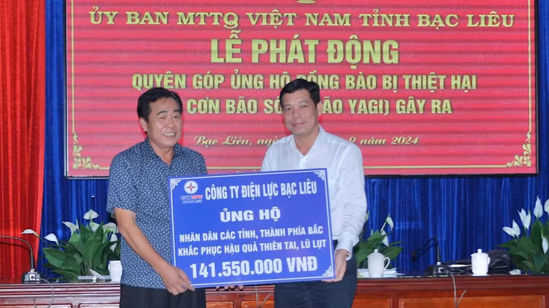 Giám đốc Công ty Điện lực Bạc Liêu Trần Hữu Khoa (bên trái) trao số tiền ủng hộ hơn 141 triệu đồng.