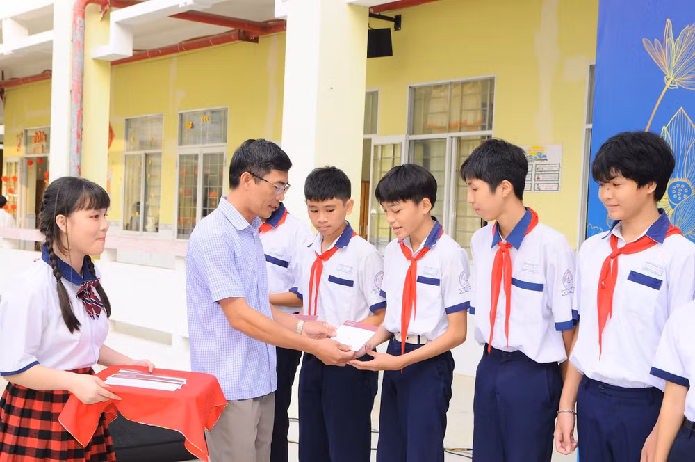 Thầy giáo Trần Văn Thịnh, Hiệu phó Trường trung học cơ sở Lê Thị Cẩm Lệ trao quà Tết của Báo Nhân Dân và Ngân hàng Nông nghiệp và Phát triển nông thôn tỉnh Bạc Liêu.