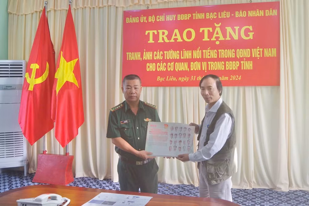Đại tá Hà Văn Sao (bên trái) , Chủ nhiệm Chính trị Bộ đội Biên phòng tỉnh Bạc Liêu nhận bộ tranh các vị tướng tài danh do Văn phòng đại diện Báo Nhân Dân tại Bạc Liêu trao tặng