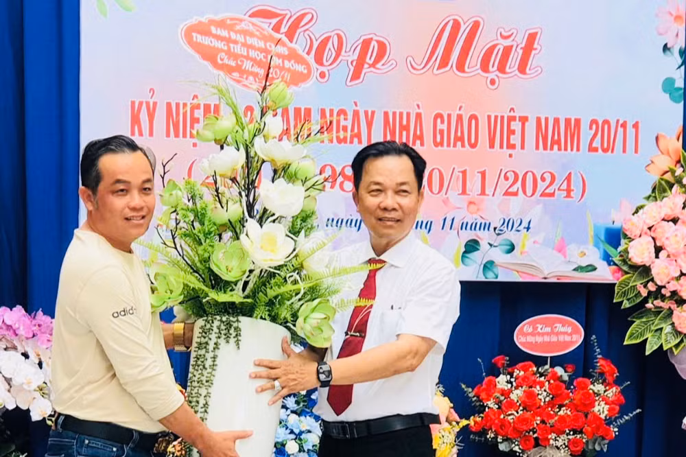 Ông Nguyễn Phú Quốc, Trưởng Ban đại diện cha mẹ học sinh Trường tiểu học Kim Đồng (thành phố Bạc Liêu) trao tặng hoa thầy Trần Văn Sơn, Bí thư Chi bộ, Hiệu trưởng Nhà trường, nhận dịp kỷ niệm 42 năm Ngày Nhà giáo Việt Nam.