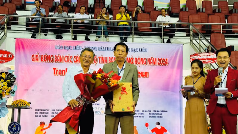 Tổng Biên tập báo Bạc Liêu Hàn Ái Tiến trao tặng hoa và cảm ơn đồng chí Nguyễn Minh Chánh (người cầm hoa), nguyên Tổng Biên tập báo Bạc Liêu và Chủ tịch Hội Nhà báo tỉnh Bạc Liêu. (Ảnh: TRỌNG DUY)