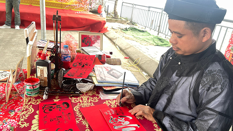 Anh Trần Hậu Thao viết chữ thư pháp tại khu di tích Đền Ông Hoàng Mười (Nghệ An).