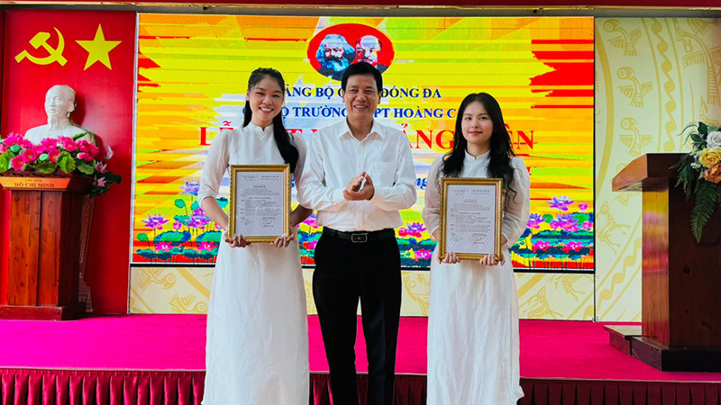 Phó Bí thư Thường trực Quận ủy Đống Đa Nguyễn Anh Cường trao quyết định kết nạp đảng viên cho hai học sinh ưu tú Trường THPT Hoàng Cầu.