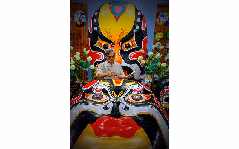 Một nghệ nhân cao niên miệt mài với từng nét vẽ cho tác phẩm “Mặt nạ thời gian” tại phường Minh An, thành phố Hội An (Quảng Nam). Ảnh: NSNA Huỳnh Hà