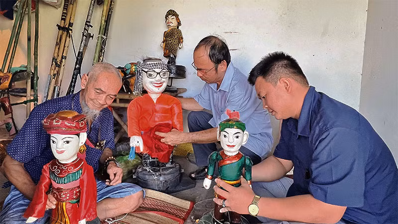 Nghệ nhân Tiến Hòa (trái) cùng các diễn viên trong đoàn chỉnh sửa con rối trước khi biểu diễn.