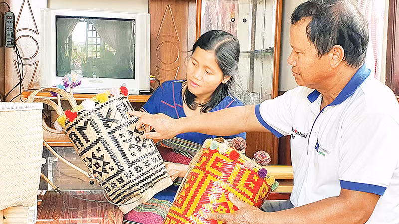 Ông Ha Pall hướng dẫn cách cài nan tạo hoa văn trên gùi cho lớp trẻ. 