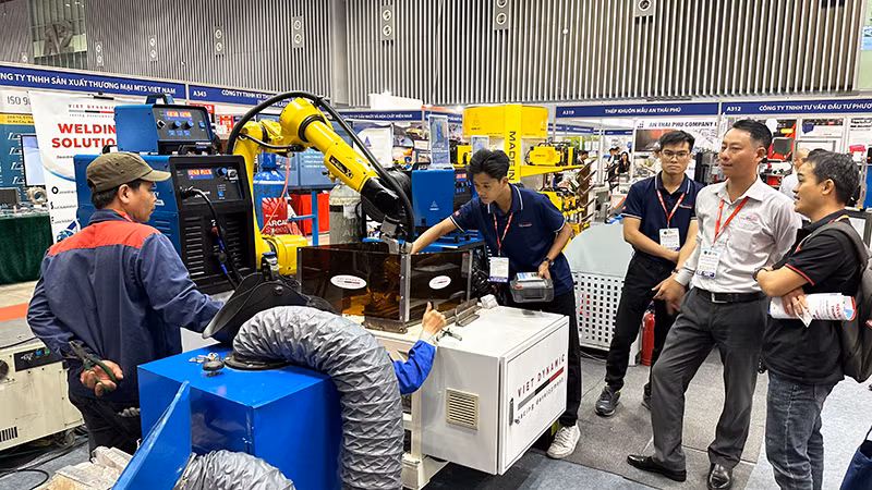 Khách tham quan tìm hiểu máy móc, thiết bị, công nghệ mới tại một gian hàng trong triển lãm
