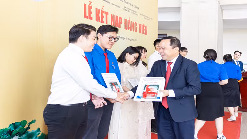 Đồng chí PGS,TS Vũ Hải Quân, Bí thư Đảng ủy, Giám đốc Đại học Quốc gia Thành phố Hồ Chí Minh trao quyết định kết nạp Đảng cho các sinh viên, giảng viên trẻ có thành tích trong nghiên cứu khoa học, công bố… (ảnh: CTV).