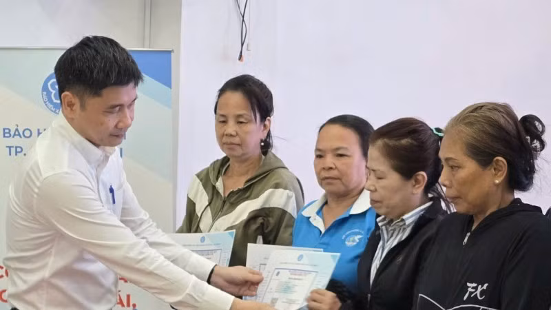 Ông Trần Dũng Hà, Phó Giám đốc Bảo hiểm xã hội Thành phố Hồ Chí Minh trao thẻ Bảo hiểm y tế cho phụ nữ có hoàn cảnh khó khăn. (Ảnh: QUÝ HIỀN)