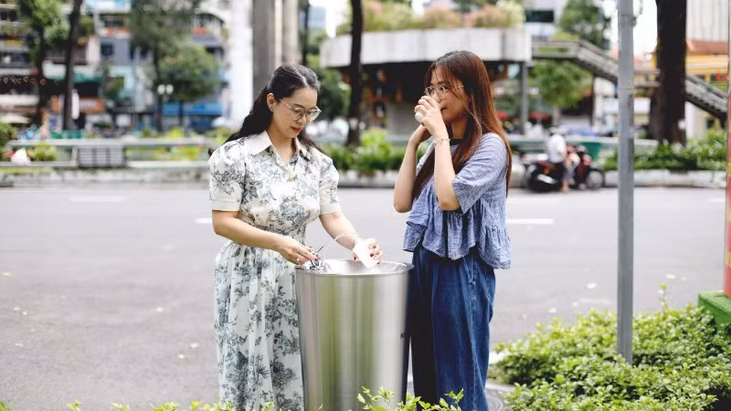 Các bạn trẻ sử dụng trụ nước uống tại vòi đặt ở Khu vực Hồ Con Rùa. (Ảnh: QUÝ HIỀN)