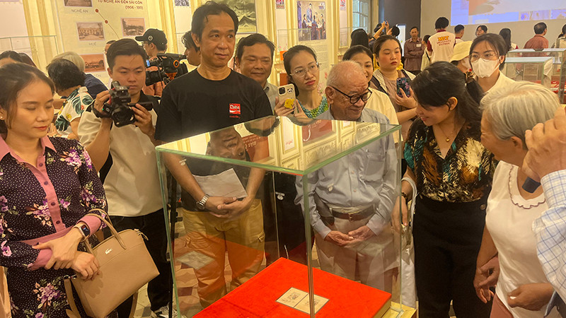 Khách tham quan thưởng lãm block tem kỷ niệm 70 năm Ngày sinh Chủ tịch Hồ Chí Minh có chữ ký của Người. (Ảnh: M.H)