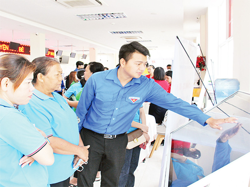Đoàn viên, thanh niên hướng dẫn người dân thực hiện giao dịch hành chính qua nền tảng công nghệ tại UBND huyện Nhà Bè. (Ảnh THẾ ANH)
