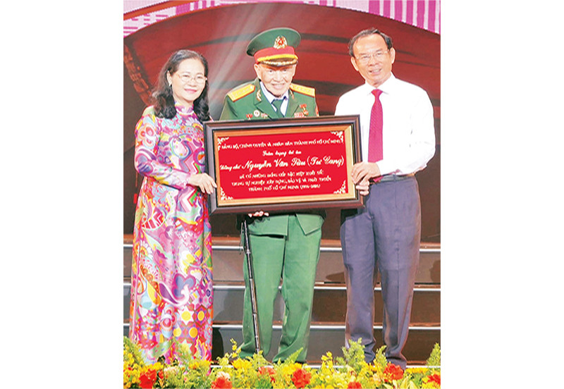 Đồng chí Nguyễn Văn Nên, Ủy viên Bộ Chính trị; Bí thư Thành ủy Thành phố Hồ Chí Minh trao bảng tôn vinh Đại tá, Anh hùng Lực lượng Vũ trang nhân dân Nguyễn Văn Tàu (Tư Cang).