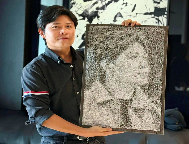 Nhạc sĩ Nguyễn Văn Chung bên bức tranh đinh chỉ nghệ thuật thể hiện chân dung mình. (Ảnh NVCC)