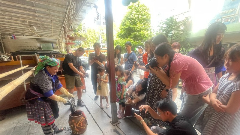 Du khách thích thú xem nghệ nhân người dân tộc Mông nhuộm vải. (Ảnh: VƯƠNG DIỆM)