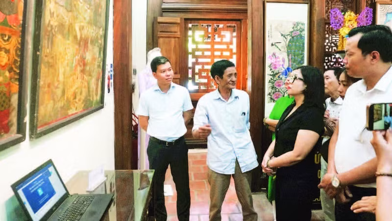 Nghệ nhân Lê Đình Nghiên (thứ hai từ trái sang) giới thiệu về tranh Hàng Trống trong triển lãm Phục hồi tại đình Nam Hương, quận Hoàn Kiếm.