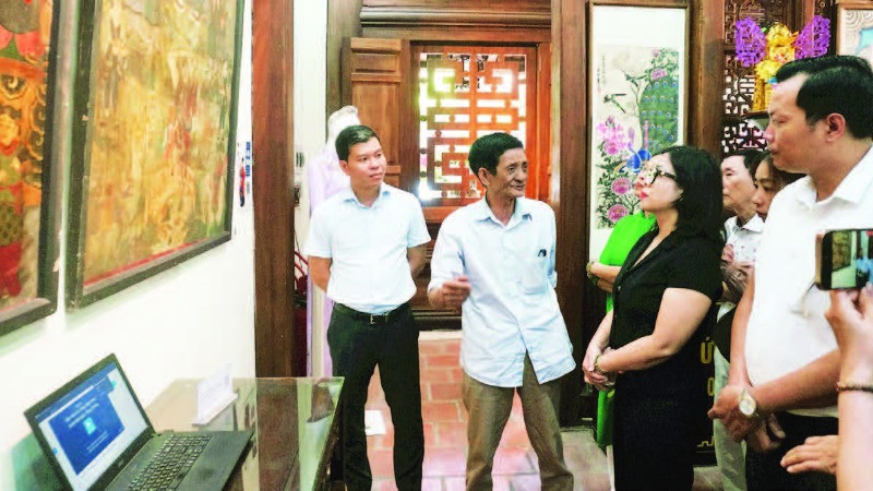 Nghệ nhân Lê Đình Nghiên (thứ hai từ trái sang) giới thiệu về tranh Hàng Trống trong triển lãm Phục hồi tại đình Nam Hương, quận Hoàn Kiếm.