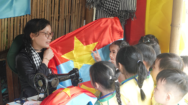 Các em nhỏ tìm hiểu về cờ giải phóng tại buổi khai mạc triển lãm. (Ảnh: MẠNH HẢO)