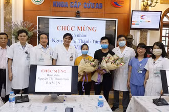 Các thầy thuốc tặng hoa chúc mừng chị Tâm đã khỏe mạnh và trở về với gia đình.