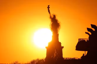 Mặt trời lặn đằng sau Tượng Nữ thần Tự do ở New York, Mỹ, tháng 5/2020. (Ảnh: AFP KEY FACTS)