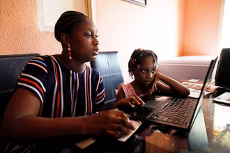 Một phụ nữ Nigeria đang cùng con học online. (Ảnh: Reuters)