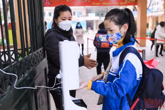 Các giáo viên trường tiểu học tại huyện Hoài Đức nhắc các em học sinh sát khuẩn tay, kiểm tra thân nhiệt trước khi vào học. (Ảnh: DUY LINH)