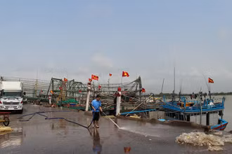Người lao động làm vệ sinh khu vực tàu cá cập Cảng Hới bốc, dỡ hải sản.
