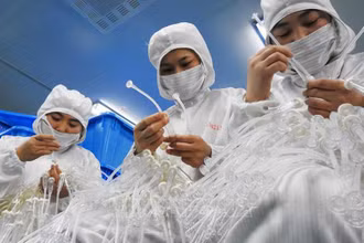Công nhân làm việc tại một nhà máy sản xuất thiết bị y tế ở tỉnh Giang Tô, Trung Quốc. Ảnh tư liệu: AFP/TTXVN
