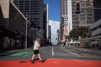 Một phụ nữ đeo khẩu trang đi trên đường phố Auckland, New Zealand ngày 18/8. 