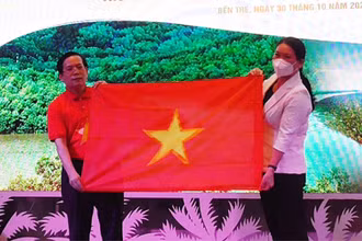 Phó Chủ tịch UBND tỉnh Bến Tre Nguyễn Thị Bé Mười nhận tượng trưng 10 nghìn lá cờ Tổ quốc từ lãnh đạo báo Người Lao Động.