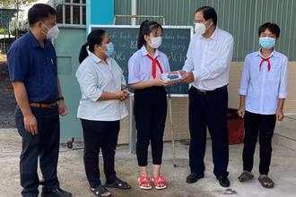 Phó Bí thư Thường trực Huyện ủy Châu Đức Nguyễn Tấn Bản (thứ 2, từ phải qua) trao thiết bị hỗ trợ học online cho em Nguyễn Uyên Nhi, học sinh lớp 7A3, Trường THCS Võ Trường Toản.