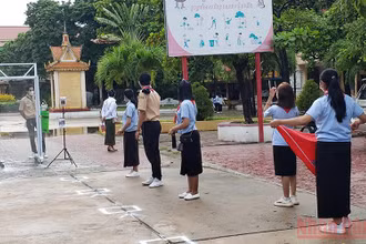 Học sinh một trường THPT tại Phnom Penh thực hiện đo thân nhiệt và khử khuẩn theo quy định.