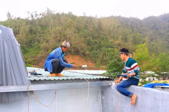 Anh Nguyễn Văn Thuận (bìa trái) sửa mái tôn cho một gia đình.