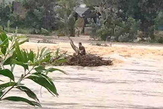 Ông Nguyễn Văn Tự đang mắc kẹt giữa dòng nước chờ cứu hộ. 