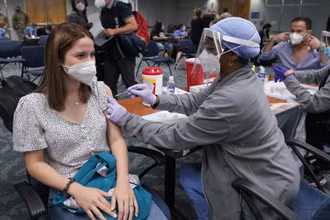 Cô Natalia Dubom (Honduras) được tiêm vaccine ngừa Covid-19 khi tới Sân bay quốc tế Miami, tại Miami, Mỹ. (Ảnh: AP)