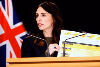 Thủ tướng New Zealand Ardern cầm bảng giới thiệu hệ thống cảnh báo Covid-19 mới tại Wellington, ngày 21-3. (Ảnh: AP)