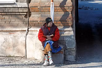 Người dân ngồi bên nhà một ngôi nhà bị hư hại do chiến sự tại Mariupol, Ukraine, ngày 7/4. (Ảnh: Reuters)