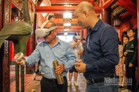 Khách du lịch thích thú khi được trải nghiệm hệ thống thực tế ảo tại di tích Văn Miếu-Quốc Tử Giám. (Ảnh: HÀ NAM)