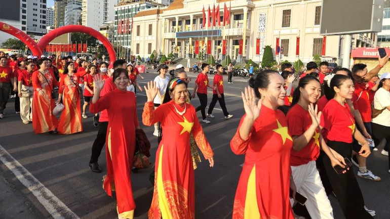 Người dân vui vẻ, tự hào với áo cờ tổ quốc cùng nhau đi bộ. 20250816-062239-1.jpg