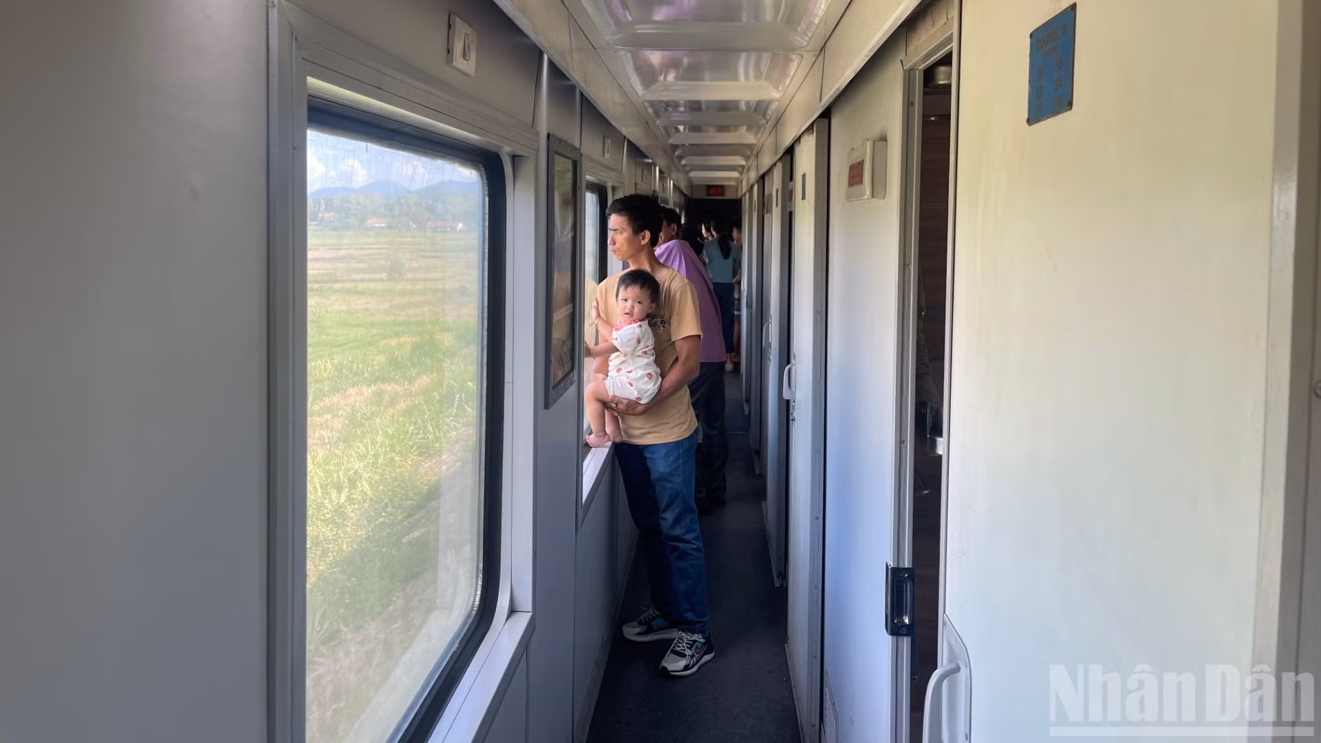 Du khách đứng ngắm cảnh qua khung cửa sổ trên tàu.