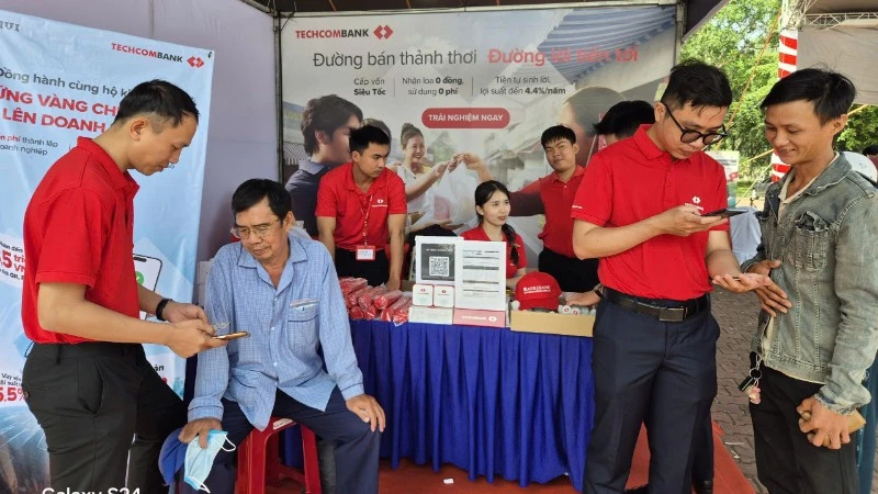 Người dân đến gian hàng của ngân hàng tham gia phiên chợ không dùng tiền mặt mở tài khoản thanh toán.