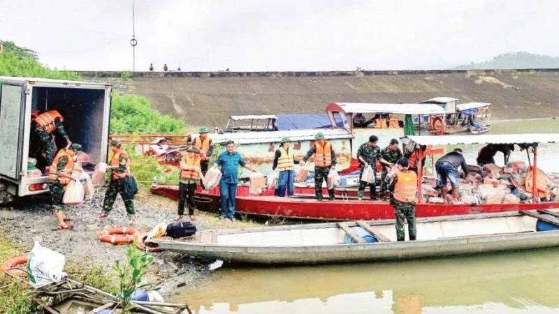 Functional forces in Tra Doc Commune load food and essential goods onto boats to cross the Tranh River and deliver supplies to isolated residents.