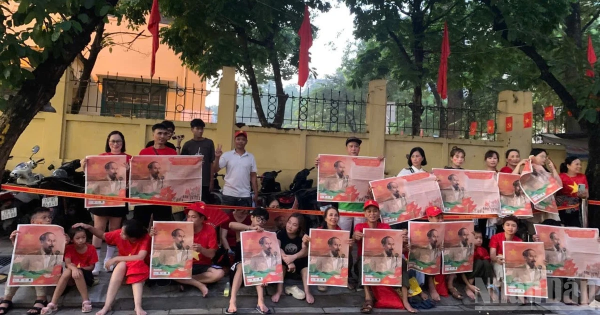 Citizens proudly hold up the Nhan Dan Newspaper special supplement featuring an image of President Ho Chi Minh welcoming the parade on Cua Bac Street.