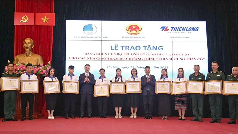Le Quan, Deputy Minister of Education and Training, and Nguyen Tuong Lam, Secretary of the Central Committee of the Ho Chi Minh Communist Youth Union and President of the Viet Nam Youth Federation, present commendation certificates to teachers at the programme.