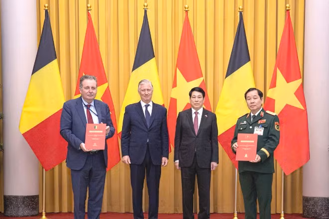Trung tướng Nguyễn Hữu Chính (ngoài cùng bên phải) và Bộ trưởng, Thủ hiến vùng Brussels, Vương quốc Bỉ (ngoài cùng bên trái) trao đổi Thỏa thuận nguyên tắc về hỗ trợ nạn nhân chất độc da cam Việt Nam, với sự chứng kiến của Nhà vua Philippe (Vương quốc Bỉ) và Chủ tịch nước Lương Cường.