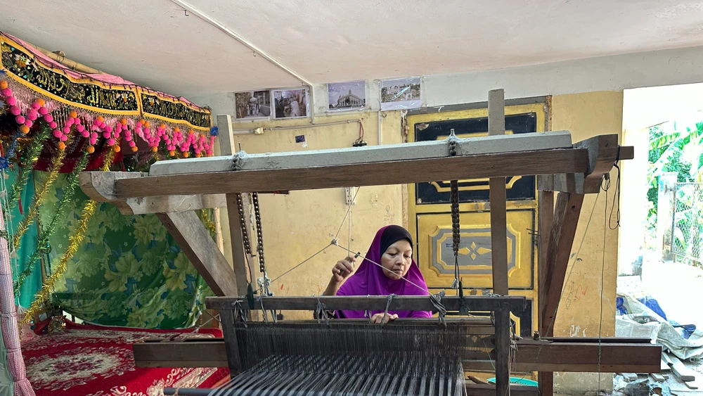 Chị Romah bên chiếc khung dệt lâu năm do mẹ để lại. (Ảnh: Thi Phong)