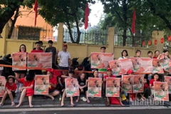 Người dân giơ cao tờ phụ san Báo Nhân Dân in ảnh Bác Hồ chào đón đoàn xe diễu binh trên đường Cửa Bắc.